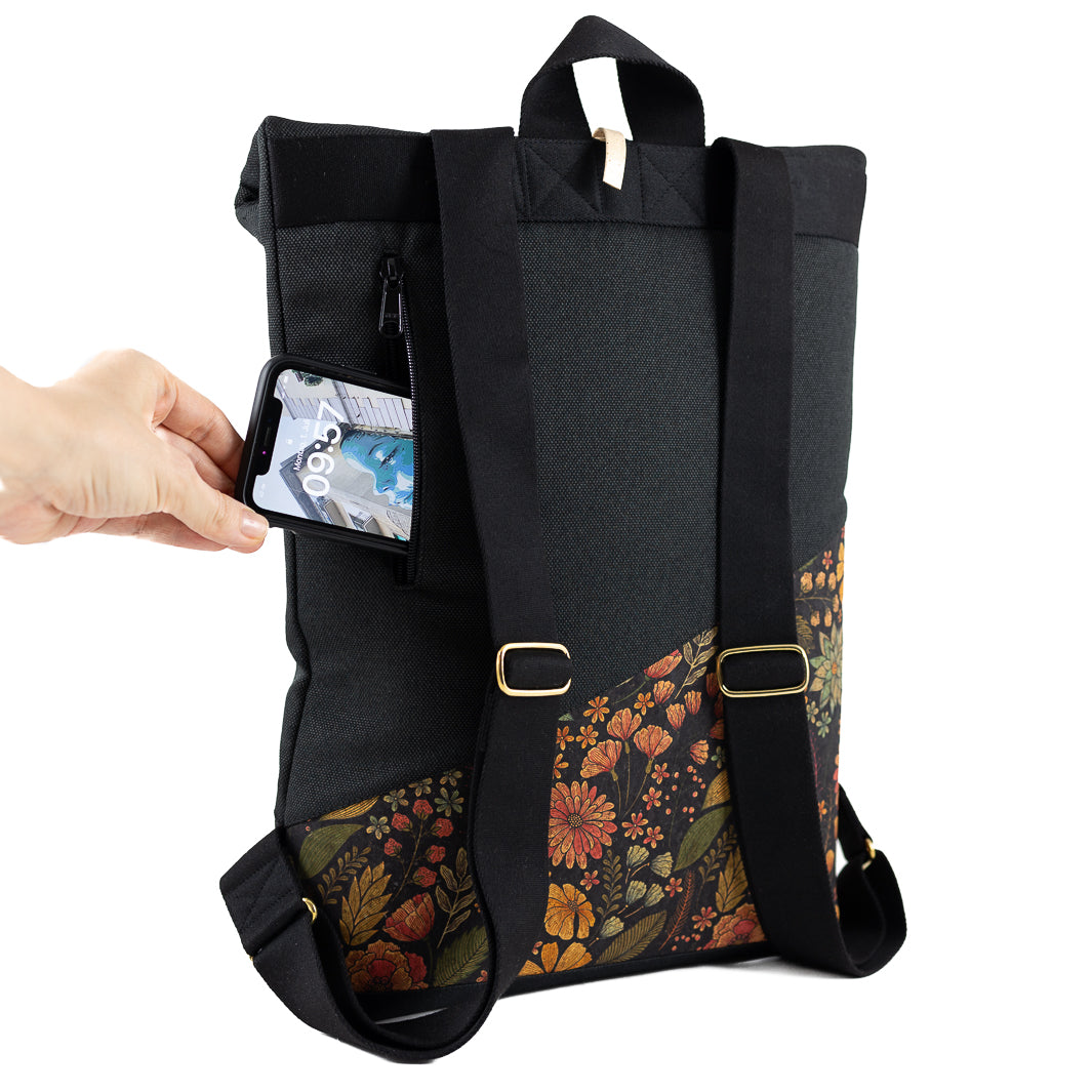 Nahaufnahme: Handy wird in das gepolsterte Geheimfach auf der Rückseite des Rolltop Rucksacks gesteckt.