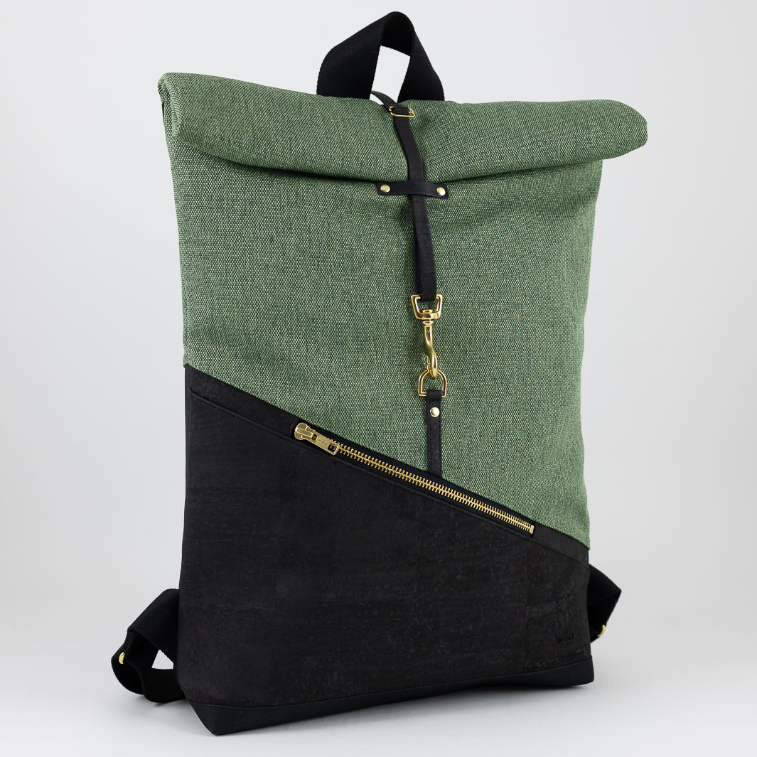 Kleiner Rolltop Rucksack in Schwarz & Waldgrün – halbseitlich fotografiert mit Blick auf das geometrische Design, den Kork und die goldenen Details