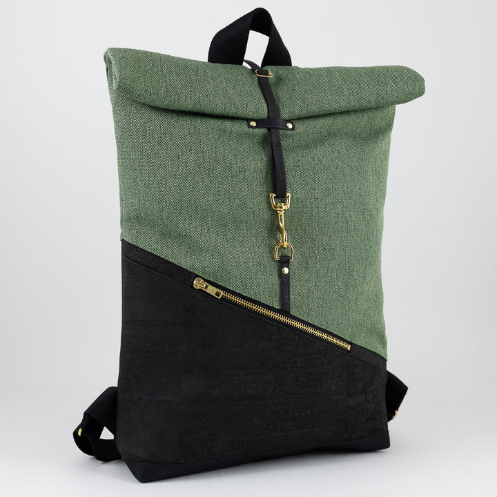 Kleiner Rolltop Rucksack in Schwarz & Waldgrün – halbseitlich fotografiert mit Blick auf das geometrische Design, den Kork und die goldenen Details