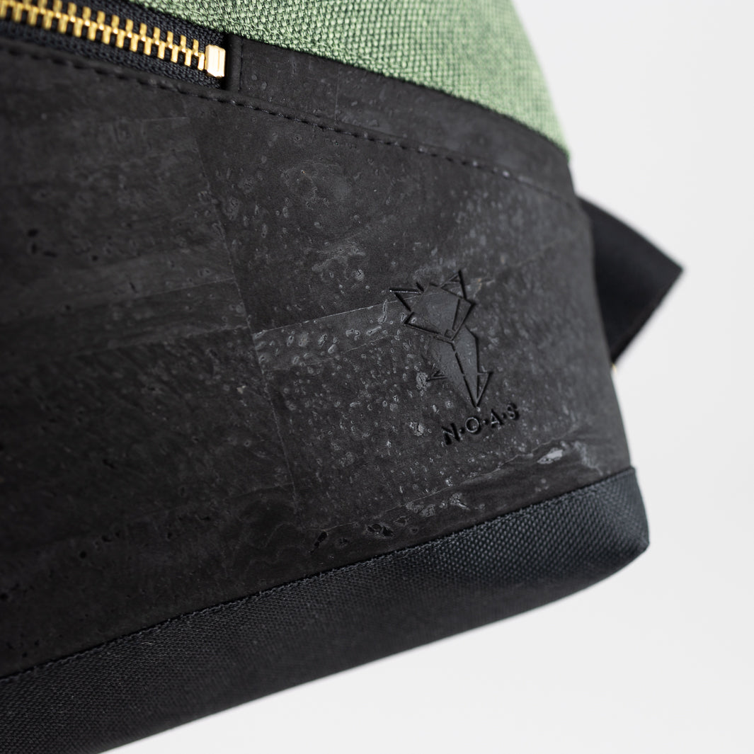 Nahaufnahme von schwarzem Kork, goldenem Karabiner und Logoprägung – hochwertiges Detail