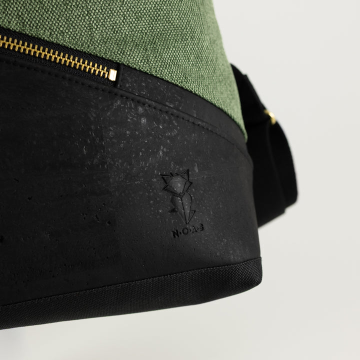 NOAS Logoprägung auf schwarzem Kork am Rolltop Rucksack mit Waldgrünem Canvas