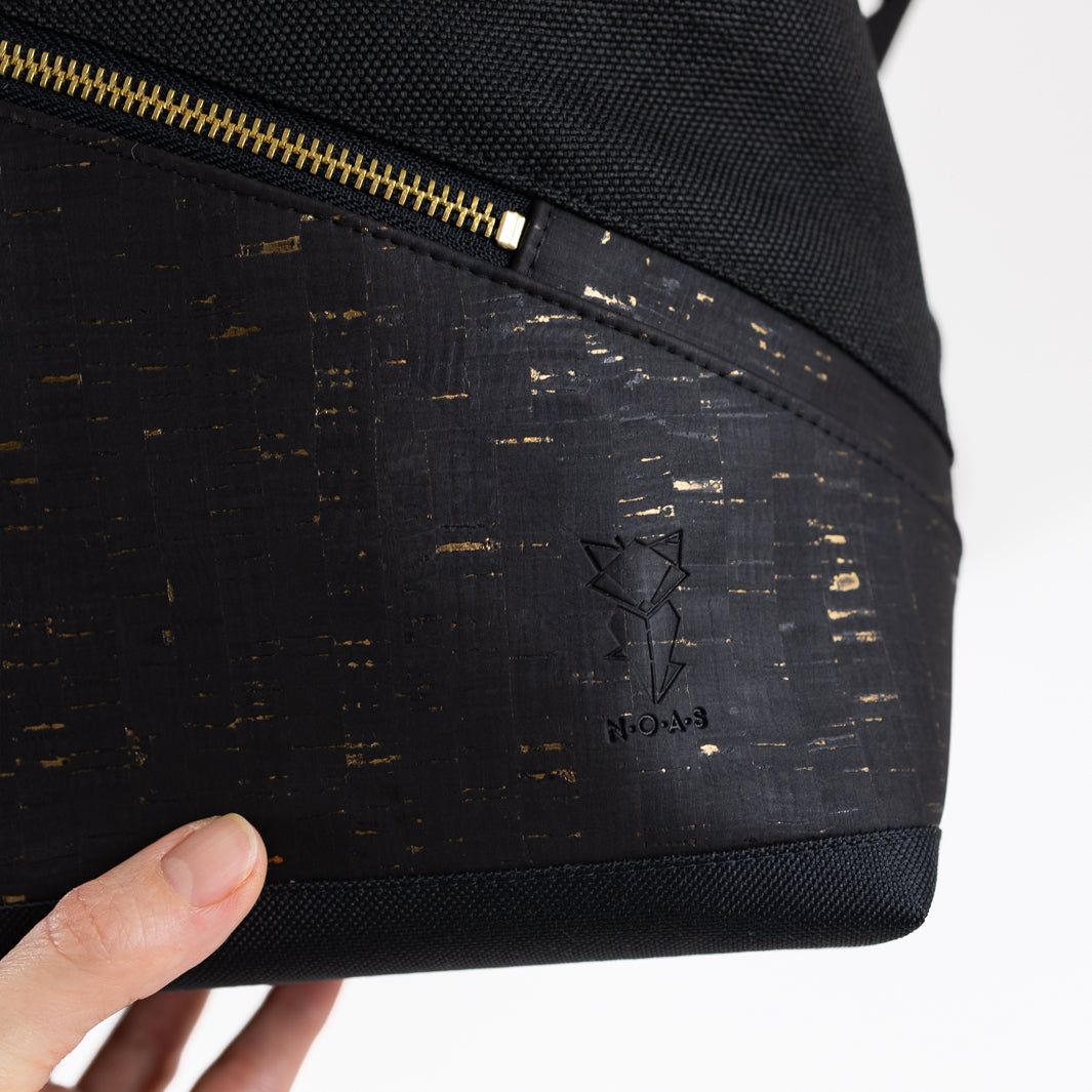Schwarzer Kork mit goldenen Details am veganen NOAS Rolltop Rucksack mit Logoprägung