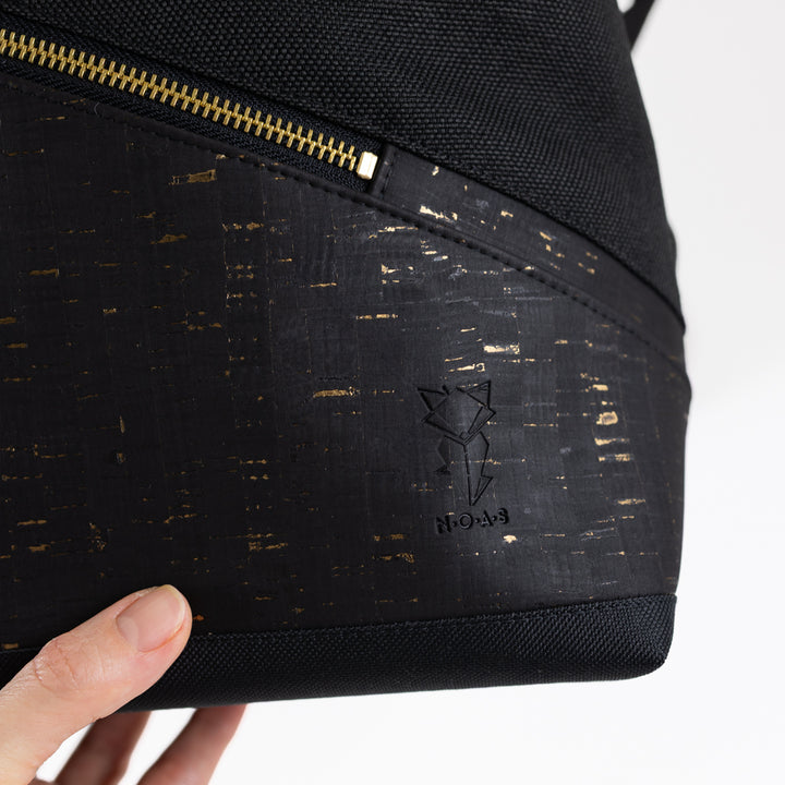 Schwarzer Kork mit goldenen Details am veganen NOAS Rolltop Rucksack mit Logoprägung
