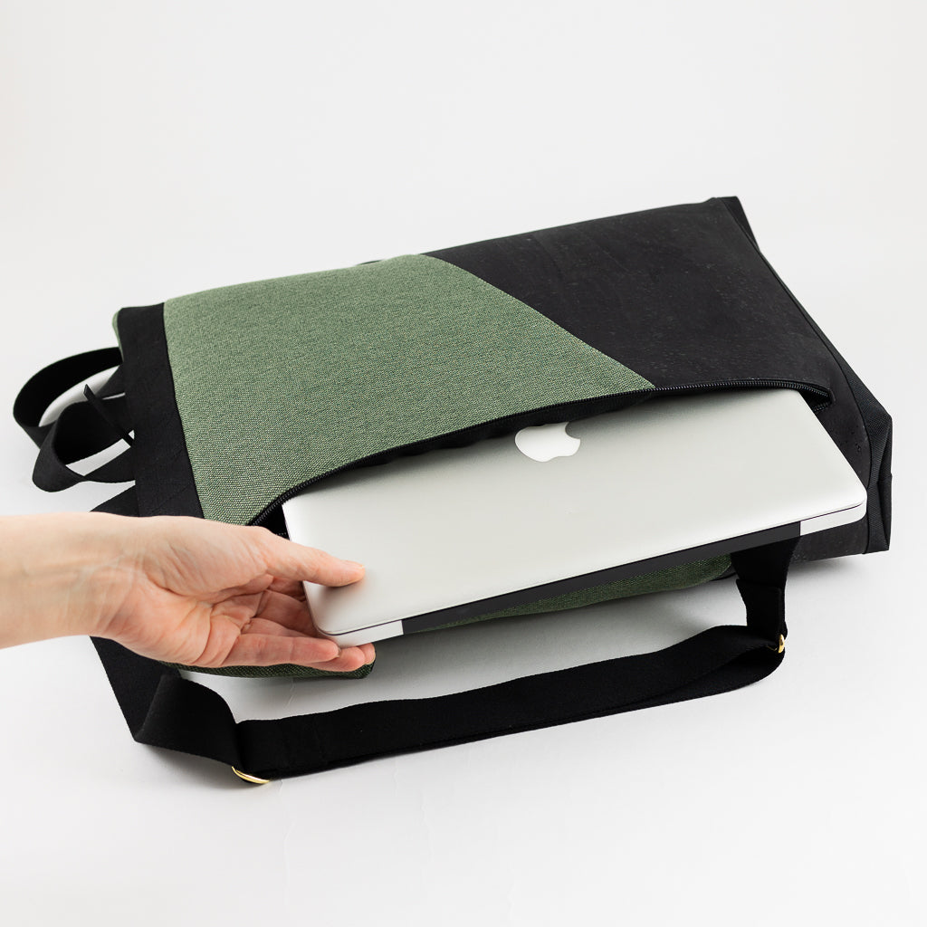 Rolltop Rucksack liegt auf der Seite, Laptop wird aus dem gepolsterten Laptopfach gezogen