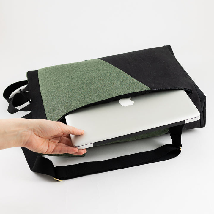 Rolltop Rucksack liegt auf der Seite, Laptop wird aus dem gepolsterten Laptopfach gezogen