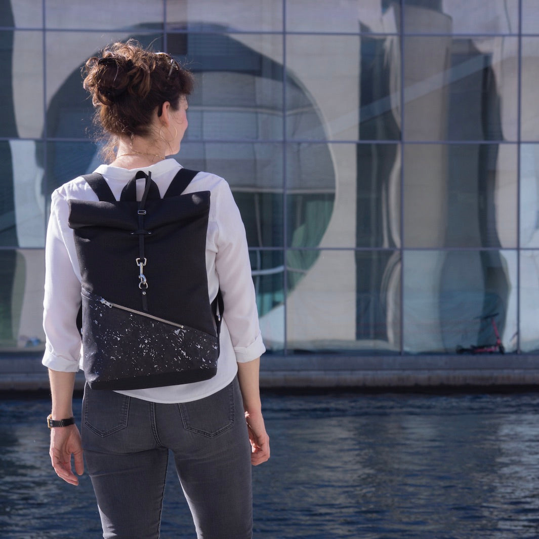 Kleiner veganer Rolltop Rucksack von NOAS Berlin – getragen im urbanen Regierungsviertel Berlin Mitte, stilvolles All-Black-Design für modernen Lifestyle.